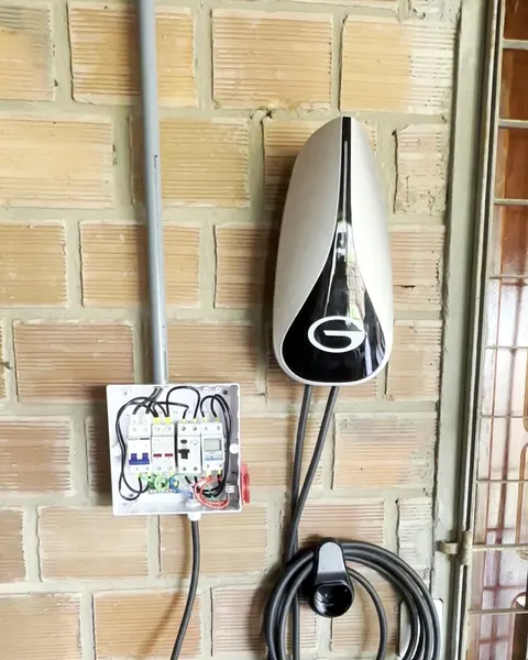 Carregador de carro elétrico na parede de tijolo, com o quadro de proteção ao lado
